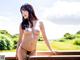 A woman in a black bikini posing on a wooden deck.