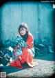 A woman sitting on the ground in front of a pile of shoes.