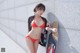 A woman in a red bikini holding a skateboard.