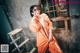 A woman in an orange jumpsuit posing for a picture.