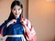 A woman in a blue and pink hanbok posing for a picture.