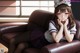 A girl in a sailor outfit sitting on a brown couch.