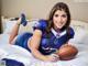 A woman laying on a bed holding a football.