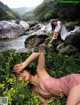 A woman laying on a rock next to a river.