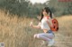 A woman crouching down in a field holding a cell phone.