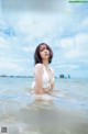 A woman in a white bikini standing in the water.