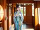 A woman in a blue kimono standing in front of a door.