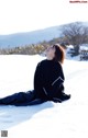 A woman sitting in the snow with her eyes closed.