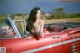A woman sitting in the back of a red convertible car.