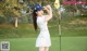 A woman in a white dress and blue hat playing golf.