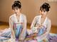 A woman in a hanbok sitting on a wooden floor.