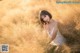 A woman in a white dress sitting in a field of tall grass.