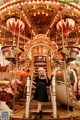 A woman in a black dress standing on a carousel.